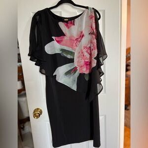 Asymmetric cocktail dress with sheer overlay. Peek-a-boo shoulder.